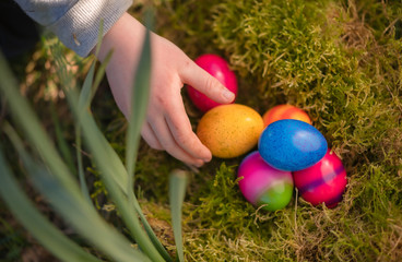 Kinderhand greift nach Ostereier in einem Nest
