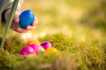 Kinderhand greift nach Ostereier in einem Nest