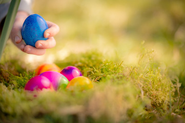 Kinderhand greift nach Ostereier in einem Nest