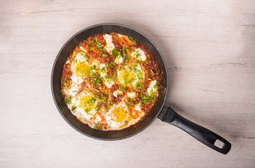 Freshly cooked shakshuka in a pan on wooden background