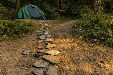 travel and camping life style concept outside picture with stone rustic trail go to tent camp site unfocused background scenic view