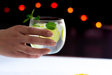 An unrecognizable person is taking  a refreshing mojito cocktail