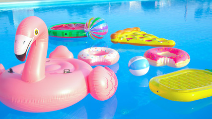 CLOSE UP: Trendy inflatable toys float around the empty pool on a sunny day.