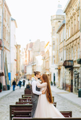 Exquisite newlyweds kissing each other against the backdrop of morning city