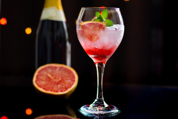 refreshing cocktail made with grapefruit and ice on black background with lights