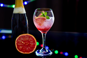 A refreshing cocktail made with grape fruit on black background with lights
