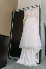 Morning of the bride: wedding dress hanging on the hotel wardrobe - 335907606