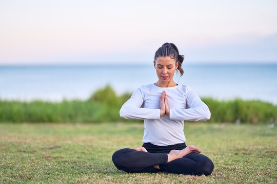 Young beautiful sportwoman practicing yoga. Coach teaching postures at park