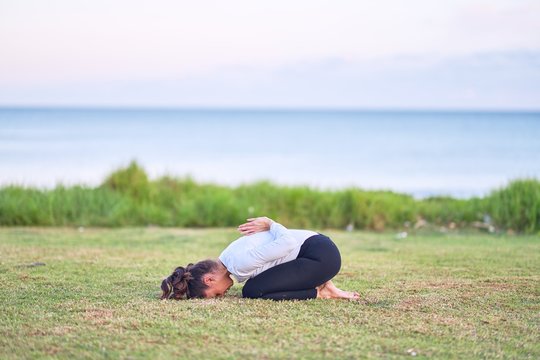 Young beautiful sportwoman practicing yoga. Coach teaching postures at park