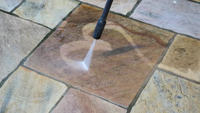 Mit einem Hochdruckreiniger ein Herz auf eine Terrassenfliese malen
