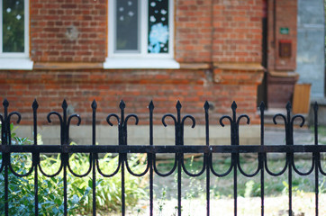 wrought iron fence carved on the background of a brick wall