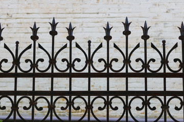 wrought iron fence carved on the background of a brick wall