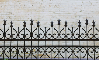 wrought iron fence carved on the background of a brick wall