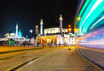 Fototapeta na wymiar Mevlana museum and city center at night with no people and passing tram light trails and rails. Konya. Turkey.06.12.2020