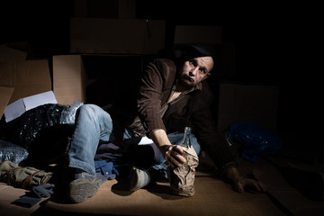 A middle-aged homeless man puts on woolen gloves.