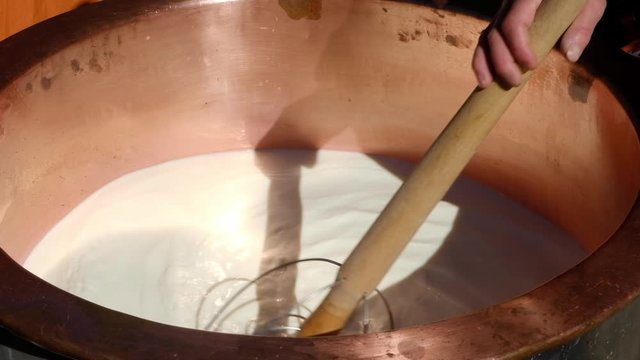 Milch im Kupferkessel r&uuml;hren um K&auml;se herzustellen