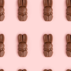 Easter bunny shaped sweets of milk chocolate laying in rows on pink background.Religious holiday composition,rabbit pattern for congratulations in greeting card.Symbol of celebration Sunday of Christ