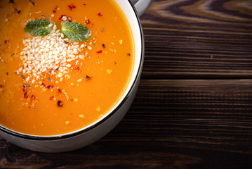 Pumpkin cream-soup in a white cup of soup with sesame and spice on the wooden table