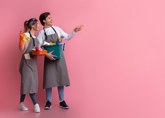 Couple Holding Buckets With Cleaning Supplies And Pointing At Copy Space