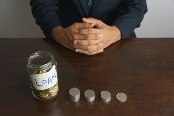financial crisis concept images. bottle of coins with text against blurred male calculating his finance report. selective focus
