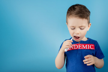 Little boy pointing to red paper with mesaage Pandemic on blue background. World Health Organization WHO