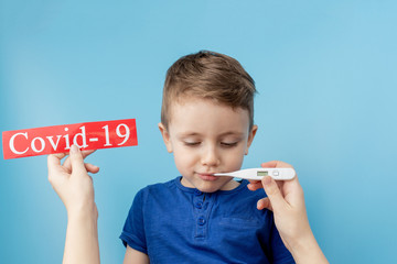 Little boy pointing to red paper with mesaage Coronavirus on blue background. World Health Organization WHO introduced new official name for Coronavirus disease named COVID-19