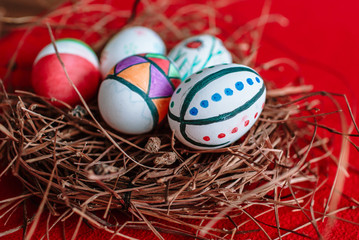 Several Easter eggs, colored with a felt-tip pen, lie in the nest, on a red background
