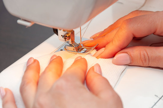 A woman sews a self-made protective face mask