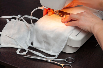 A woman sews a self-made protective face mask