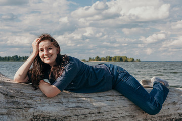 Plus size girl lies on a log by the river