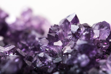 Amethyst purple crystals on white background selective focus