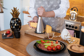 Caucasian cooker rubs cheese for different dishes on the table