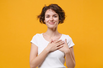 Smiling young brunette woman girl in white t-shirt posing isolated on yellow orange wall background...