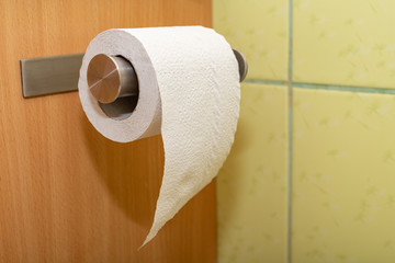 Toilet paper hung on a hanger in the bathroom. Hygienic accessories in the home toilet.