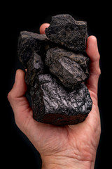 Naklejka premium Pieces of brown coal held in the palm of your hand. Material mined in mines for heating homes.