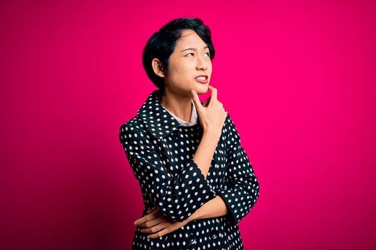 Young beautiful asian girl wearing casual jacket standing over isolated pink background Thinking worried about a question, concerned and nervous with hand on chin