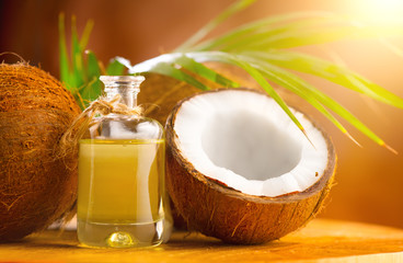 Coconut palm oil in a bottle with coconuts and green palm tree leaf on brown background. Coco nut closeup. Healthy Food, skin care concept. Vegan food. Skincare treatments. Aromatherapy. - obrazy, fototapety, plakaty