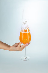 Close up of a hand holding a glass of Singapore cocktail on white background with copy space.