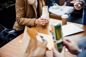 Two modern business people eating together outside