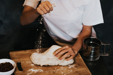 Young figured girl kneads the dough in a white T-shirt with long nails with natural manicure on a...