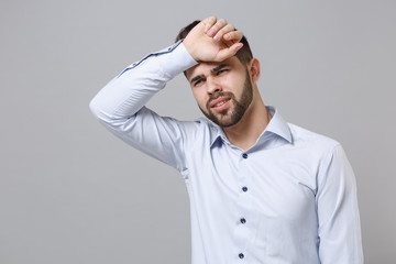 Tired exhausted young unshaven business man in light shirt posing isolated on grey wall background...