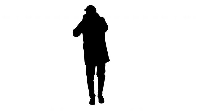 Silhouette Casual man in outdoor clothes and medical mask walking and talking on the phone.