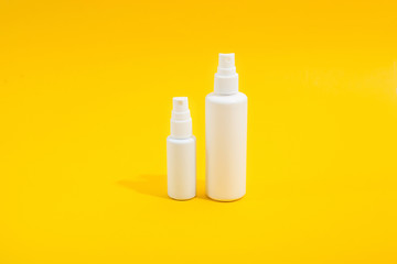 Two white plastic bottle with spray on yellow background