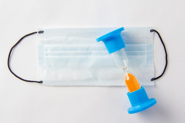 Hourglass shows time in the background with medical mask