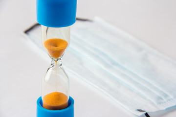 Hourglass shows time in the background with medical mask