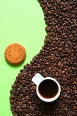 Coffee composition of a Cup with coffee and coffee beans on a green background. Coffee mood.