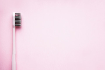 Fototapeta na wymiar Close-up pink toothbrush with space for text on pink background, flat lay composition