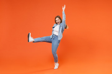 Cheerful young woman girl in casual denim clothes posing isolated on orange background studio...