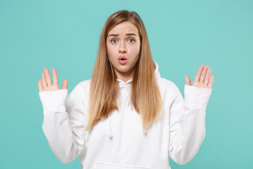 Shocked perplexed young woman girl in casual white hoodie posing isolated on blue turquoise...