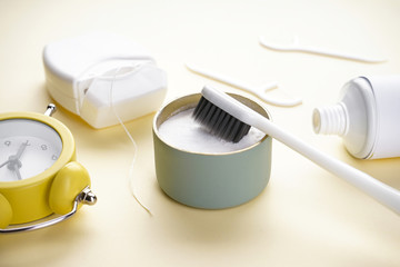 White toothbrush with tooth powder on a yellow background, close-up. Morning concept.
